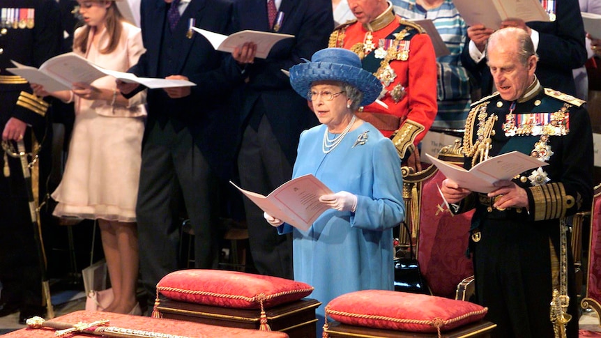 queen elizabeth singing in church setting next to prince philip, holding service booklets