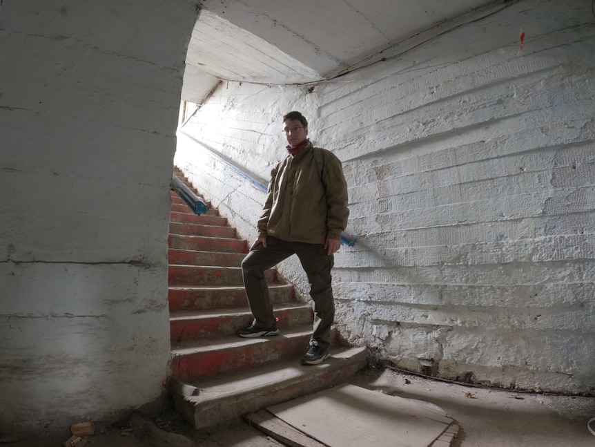 An  Odesa volunteer standing on stairways descending into the catacomb
