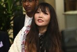 Doan Thi Huong has long hair and wears a white and red top as she walks though an airport