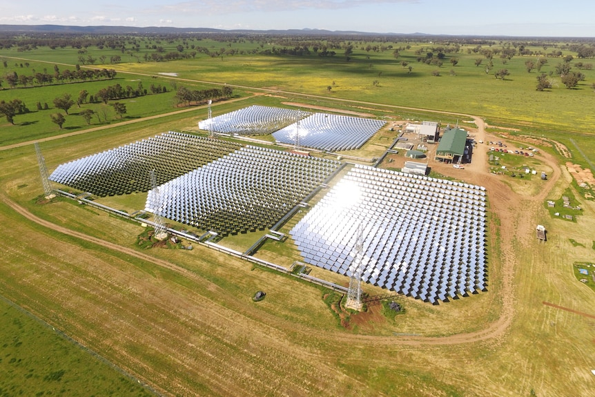 A drone photo of a solar plant wtih tall towers on each end.