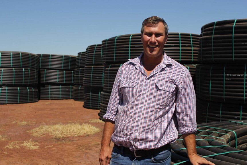 a man stands in front of stacks of poly pipe.