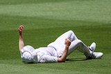 A South African cricketer lies full length on the grass after being knocked over by a mobile camera during a Test match.