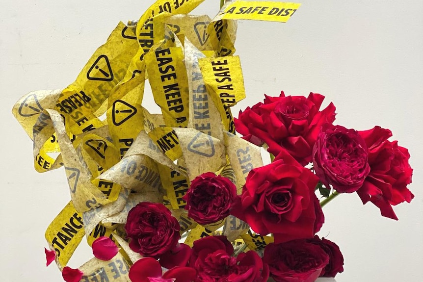 A collection of red roses next to scrunched up warning tape.