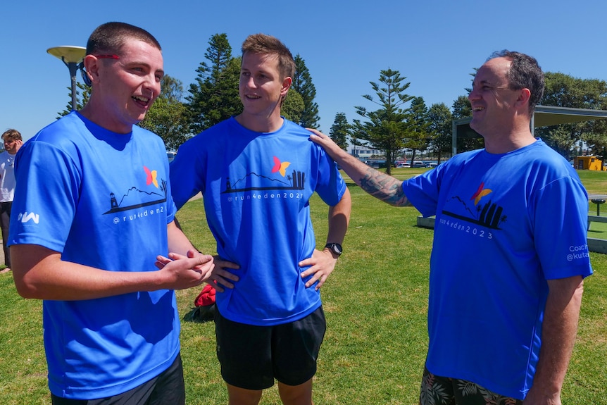 three men standing together before a mental health charity run begins. 