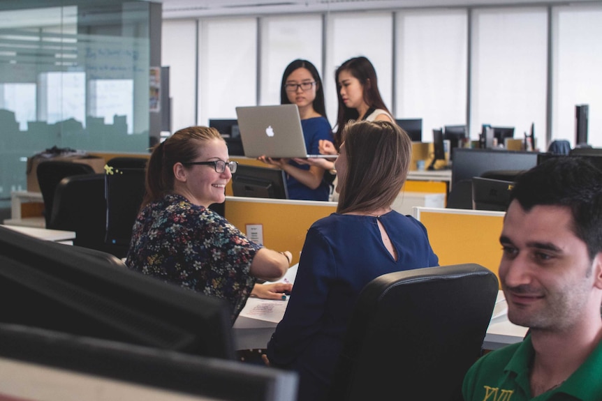 People standing and sitting close together in open plan office