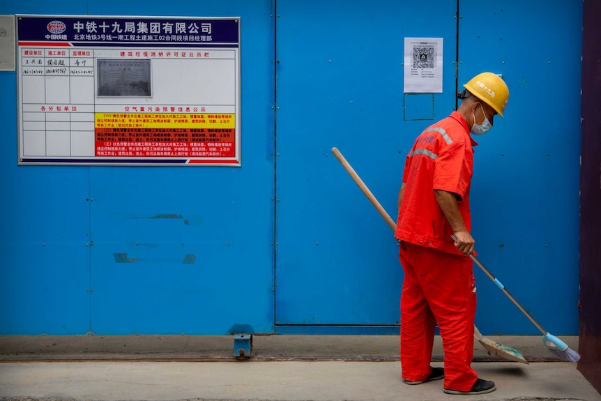 A Chinese maintenance worker wearing a face mask to protect against the coronavirus sweeps in Beijing.