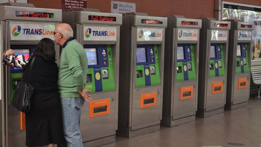 People buy tickets from a Translink machine