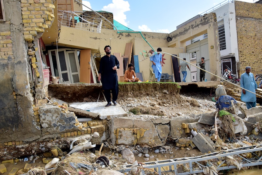 People stand in their partially damage homes caused by flooding after heavy rains.