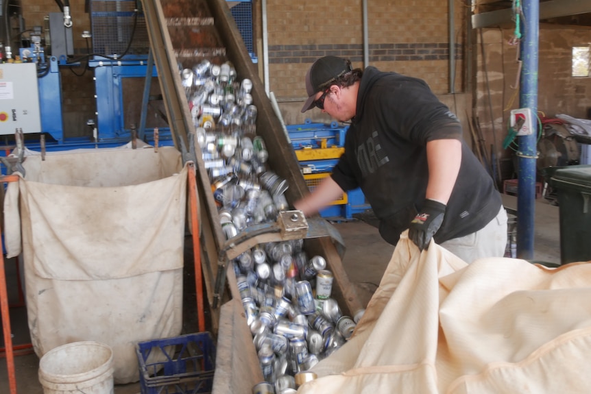 A worker at Channing's Bottle Yard pushes cans up the conveyor belt