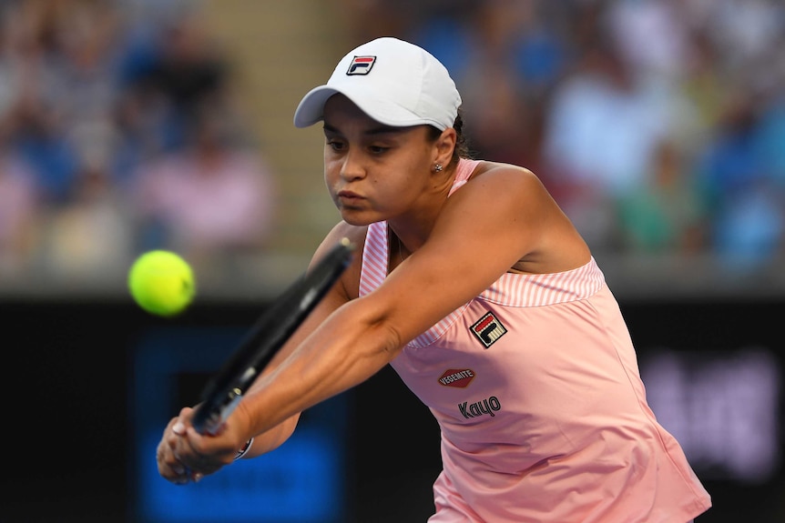 A tennis player plays a double-fisted backhand in a tennis match.