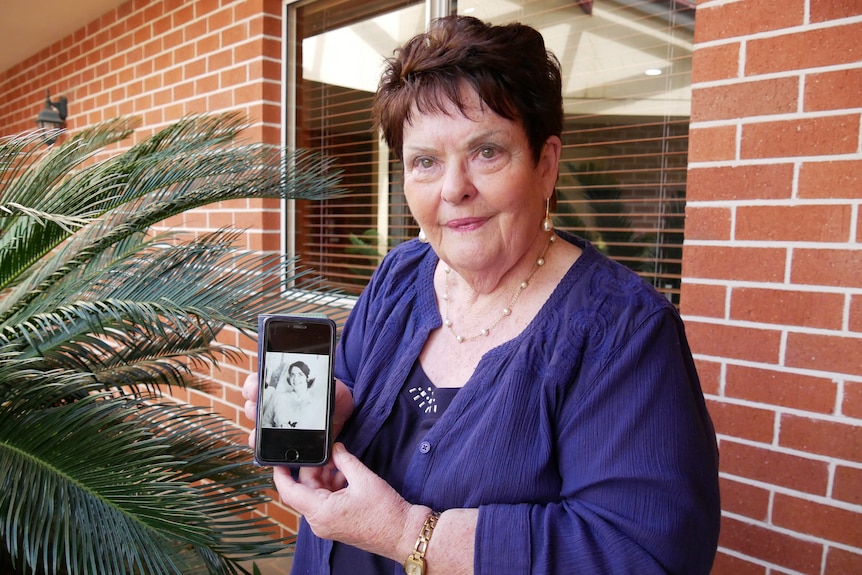 Older woman holding photo of her younger self on wedding day