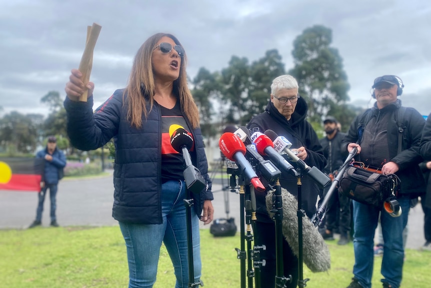 A woman speaking to a set of media microphones