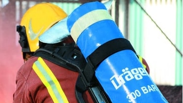 An emergency worker from the back with emergency breathing equipment strapped on