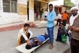 Relatives attend to a patient lying on a stretcher in the premises of a hospital in India.