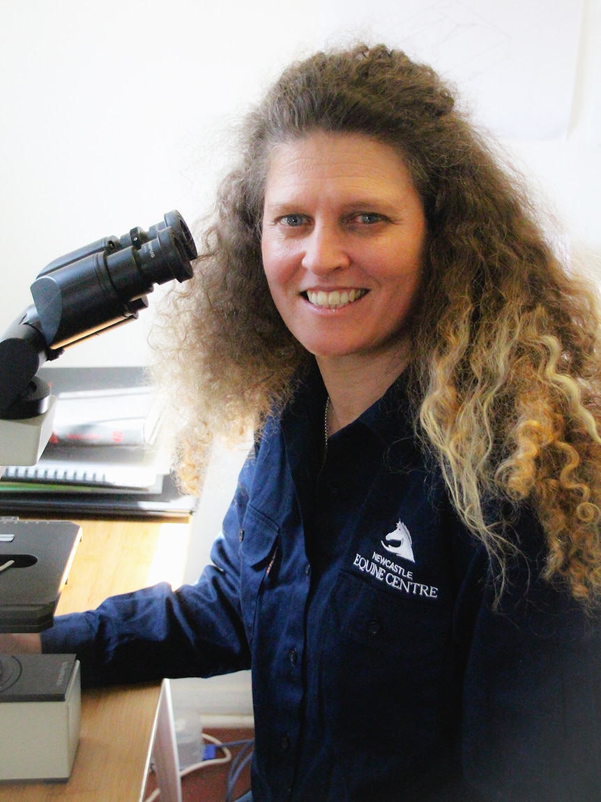 Dr Kristen Todhunter in front of a microscope.