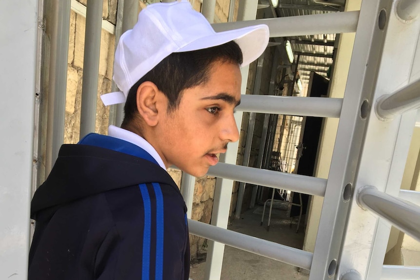 Ameer, 16, carries a large box of tomatoes into a checkpoint turnstile in downtown Hebron.