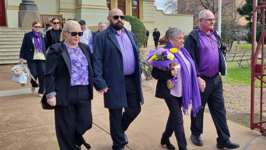 Michelle Bright's family leave court wearing black and purple, mother Loraine holdeing yellow flowers