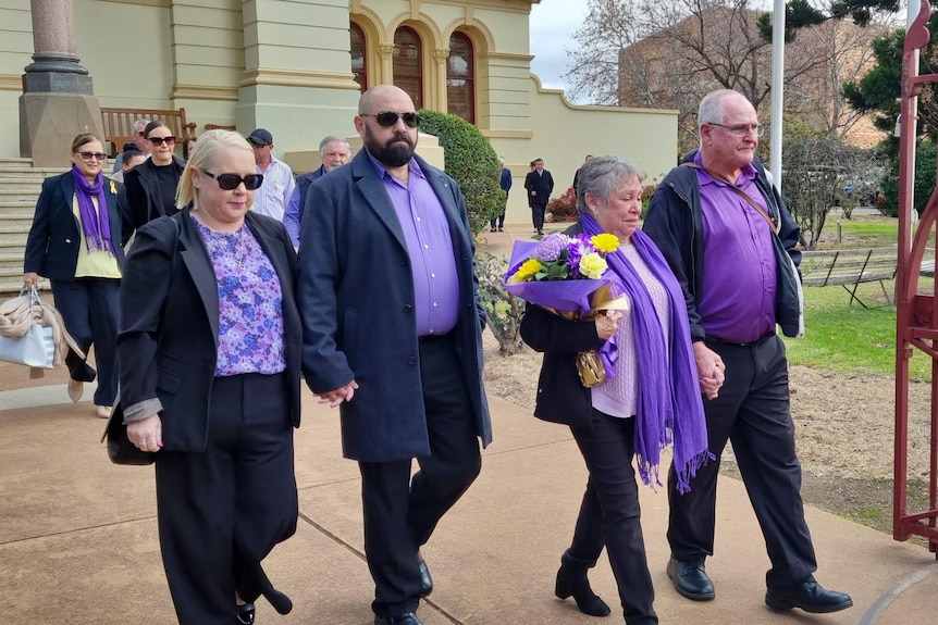Michelle Bright's family leave court wearing black and purple, mother Loraine holdeing yellow flowers