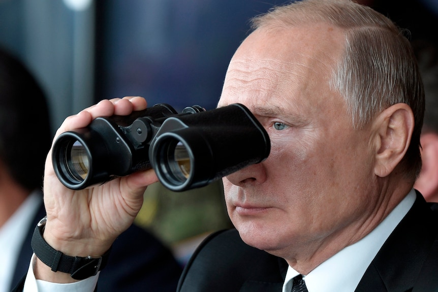 Vladimir Putin looks through a pair of binoculars