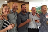 The 60 Minutes crew pose a photo in what looks to be a hotel foyer.