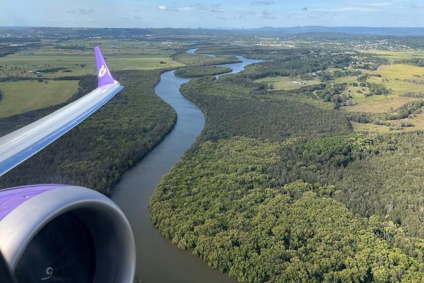 Window view out of airplane showing greenery and river