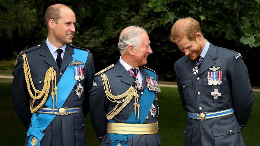 Prince Charles grinning while standing between his sons William and Harry