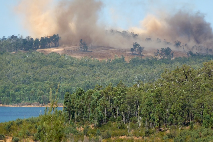 A large cloud of mining dust near a body of water used for drinking.