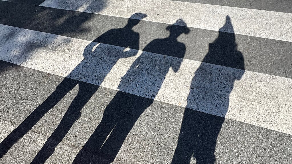 Shadows of three people on a pedestrian crossing