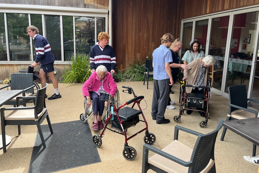 Students help aged care residents get into their wheelchairs.