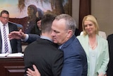 Two men embrace in a parliament as a gun control law passes