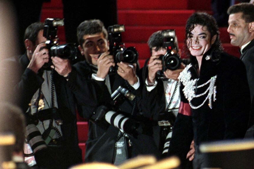Photographers surrounding Michael Jackson. 