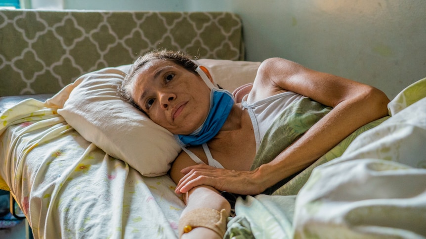 A woman lying in a hospital bed with an IV drip in her arm