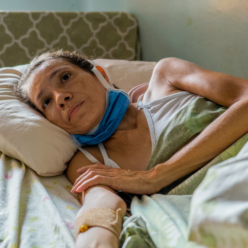 A woman lying in a hospital bed with an IV drip in her arm