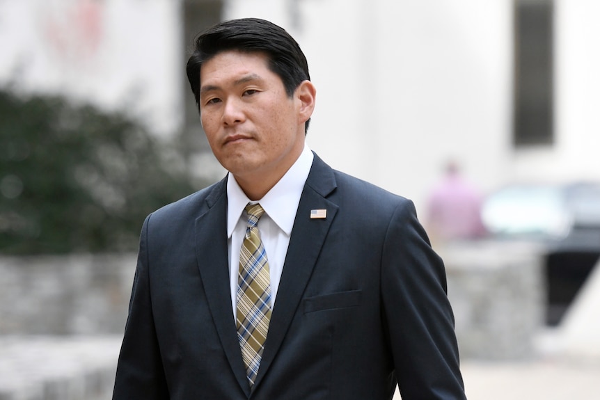 US Attorney Robert Hur walks in the street wearing a suit and tie.