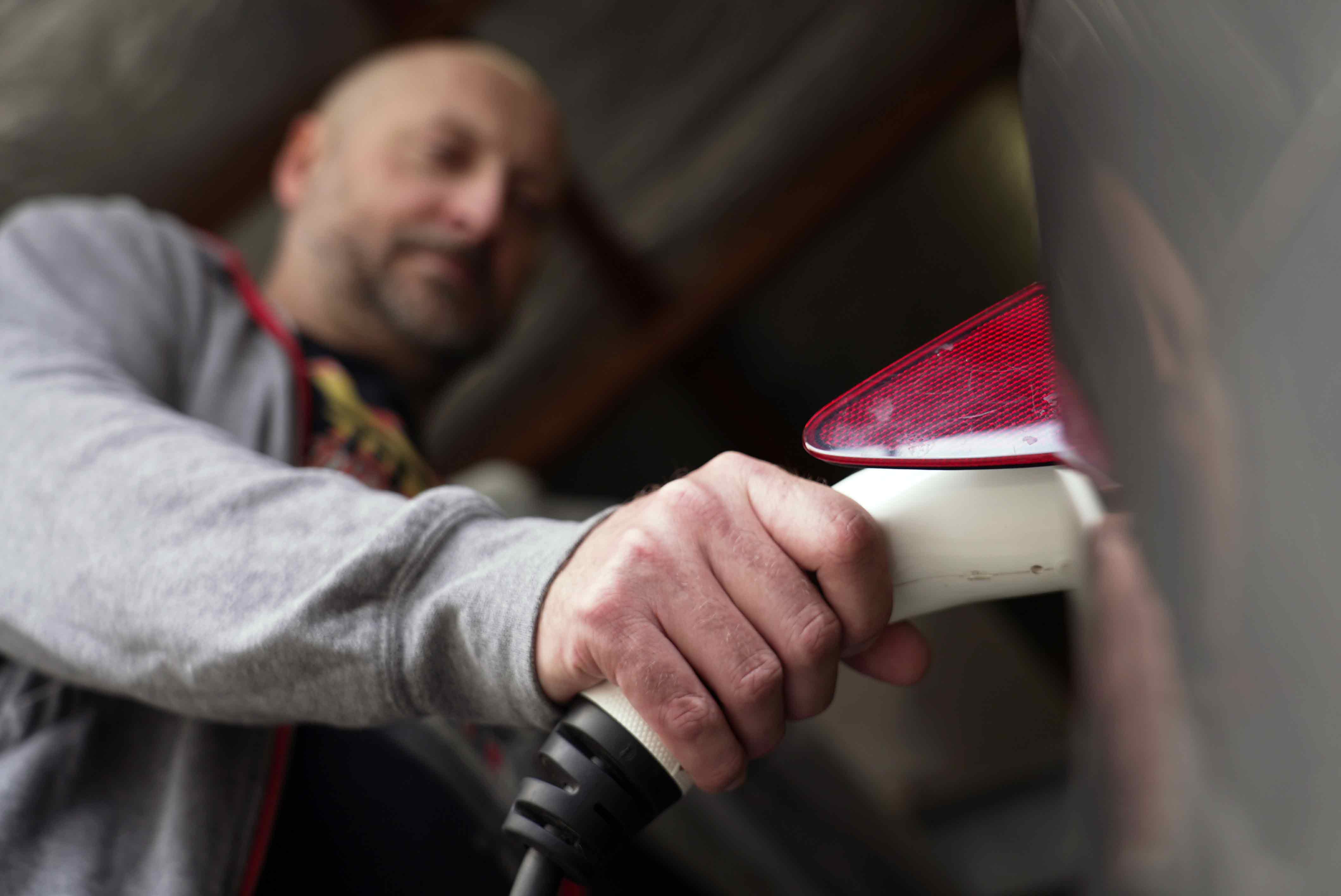 A close-up of an EV charger in the car slot, operated by Richard Chapman in the background