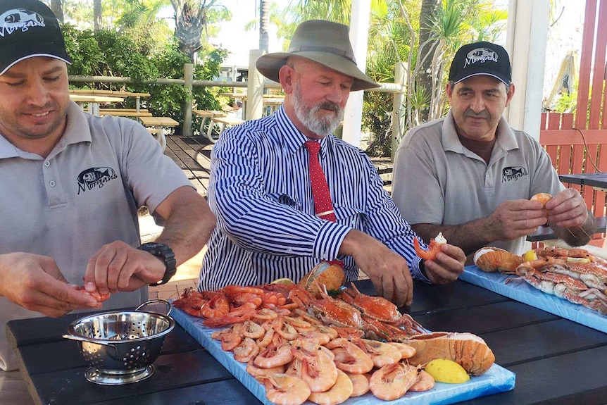 Bill Byrne (centre) eating prawns with Morgan's Seafood employees