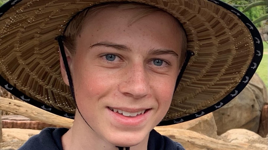 A teenage boy wearing a wide-brimmed straw hat