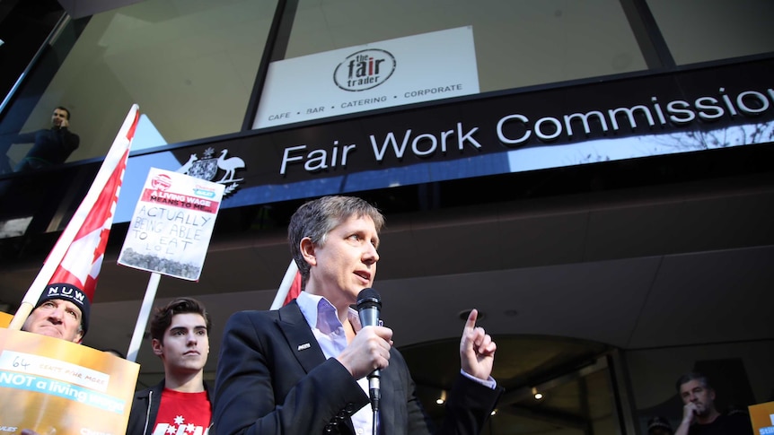 Sally McManus holds a microphone while addressing unionists outside the Fair Work Commission building in Melbourne.
