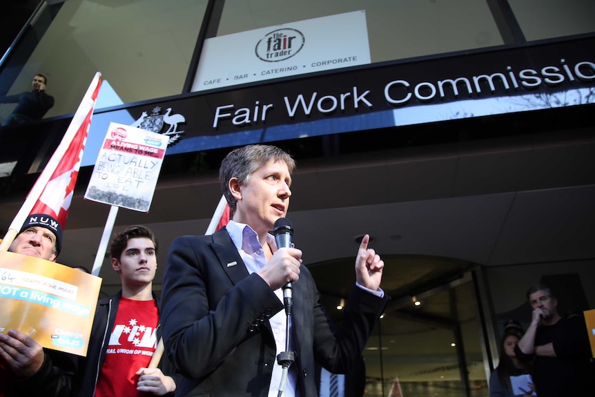 Sally McManus holds a microphone while addressing unionists outside the Fair Work Commission building in Melbourne.