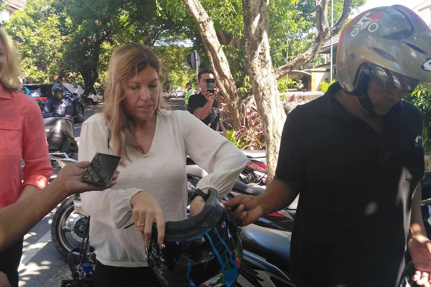 Mercedes Corby puts on a helmet as media gather to ask her questions.