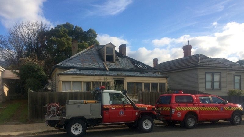 Police vehicles in front of a fire-damaged house in Hobart's Sandy Bay.