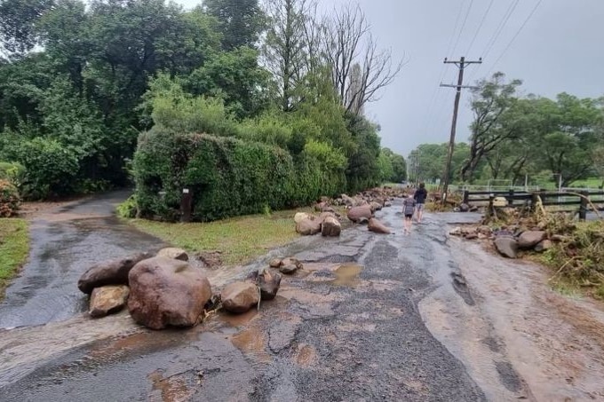 Large rocks strewn on a wet country road.