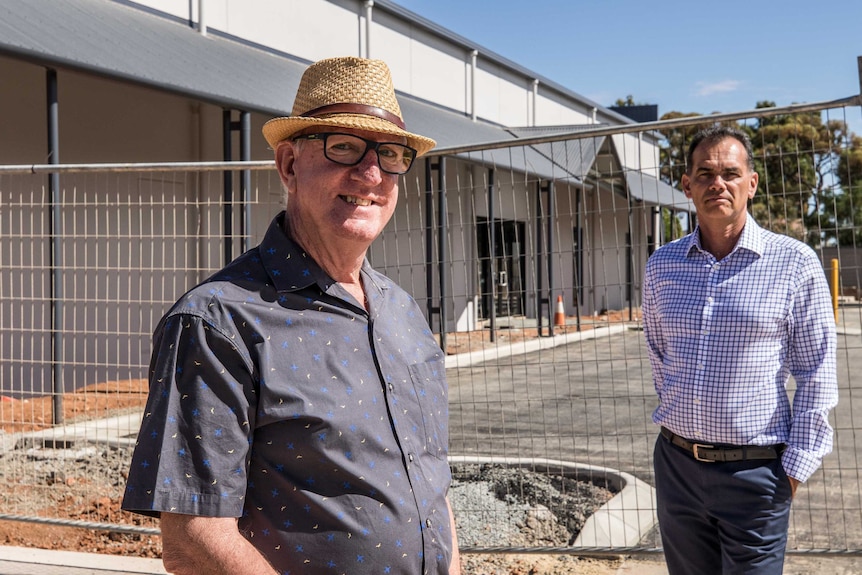 Two men standing outside a construction site for a new church.