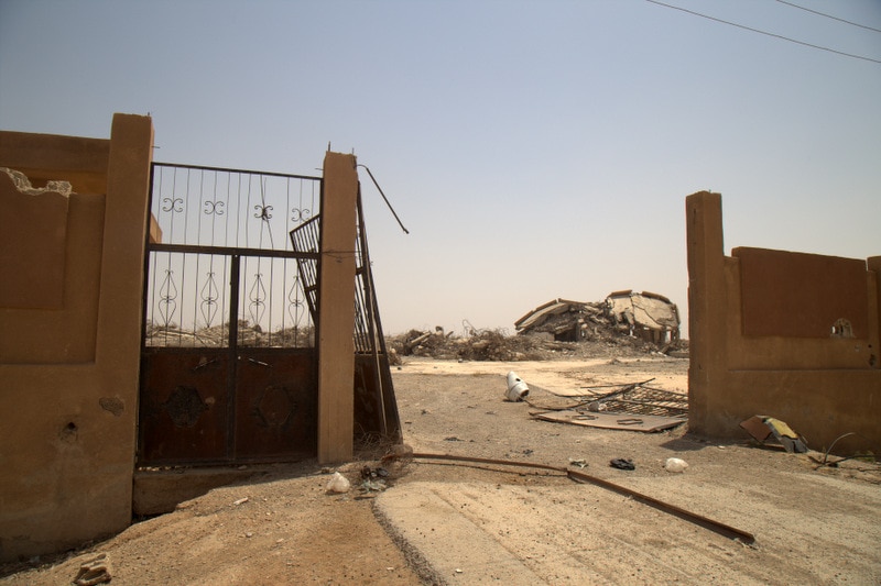 A destroyed building is seen through crumbling gates.