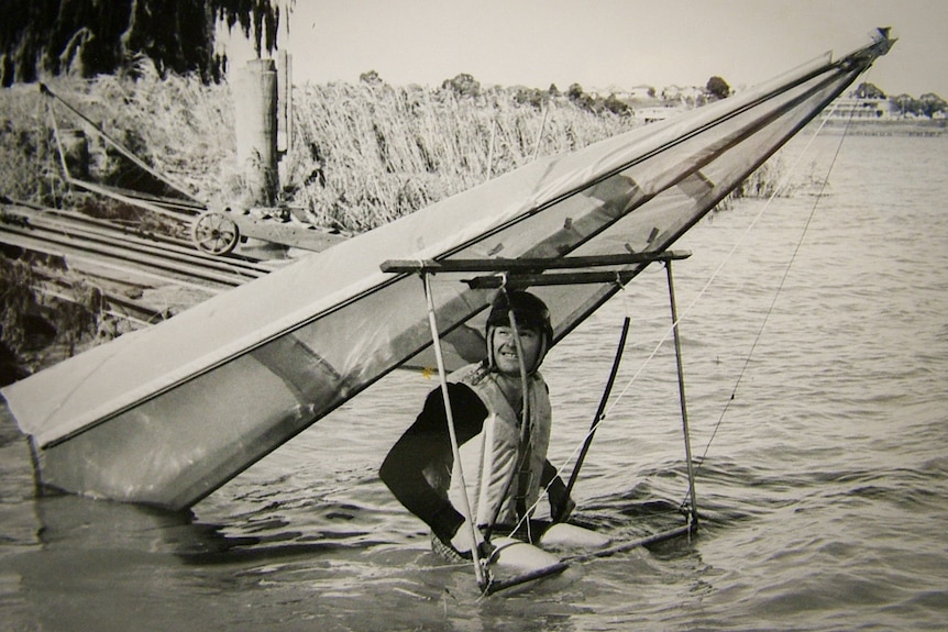 Man attached to a small glider sitting in a river