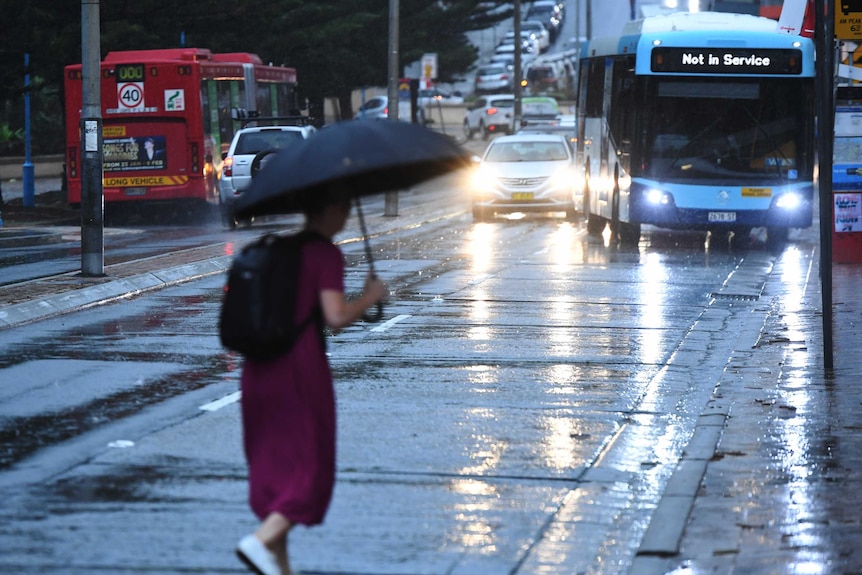 personne marchant dans une rue mouillée avec un bus qui dit qu'il n'est pas en service