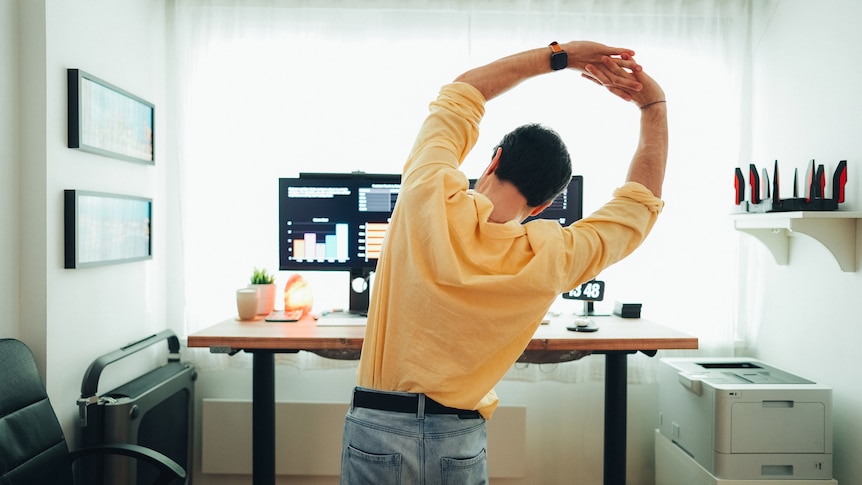 man stretching in front of his desk while standing