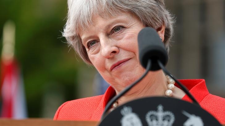 Theresa May smiles behind podium