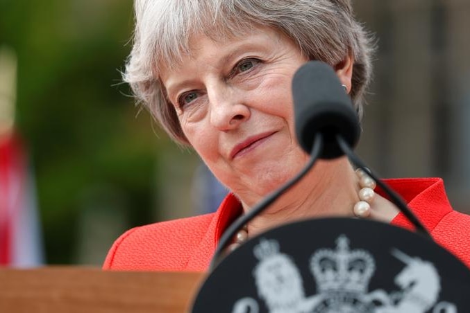 Theresa May smiles behind podium