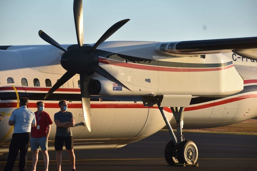 Close up of a plan on the tarmac with three men standing beside it and a painted Australian flag visible on the wing.